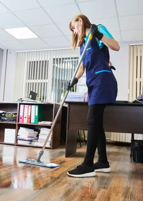 A cleaning operative mops a communal office space.